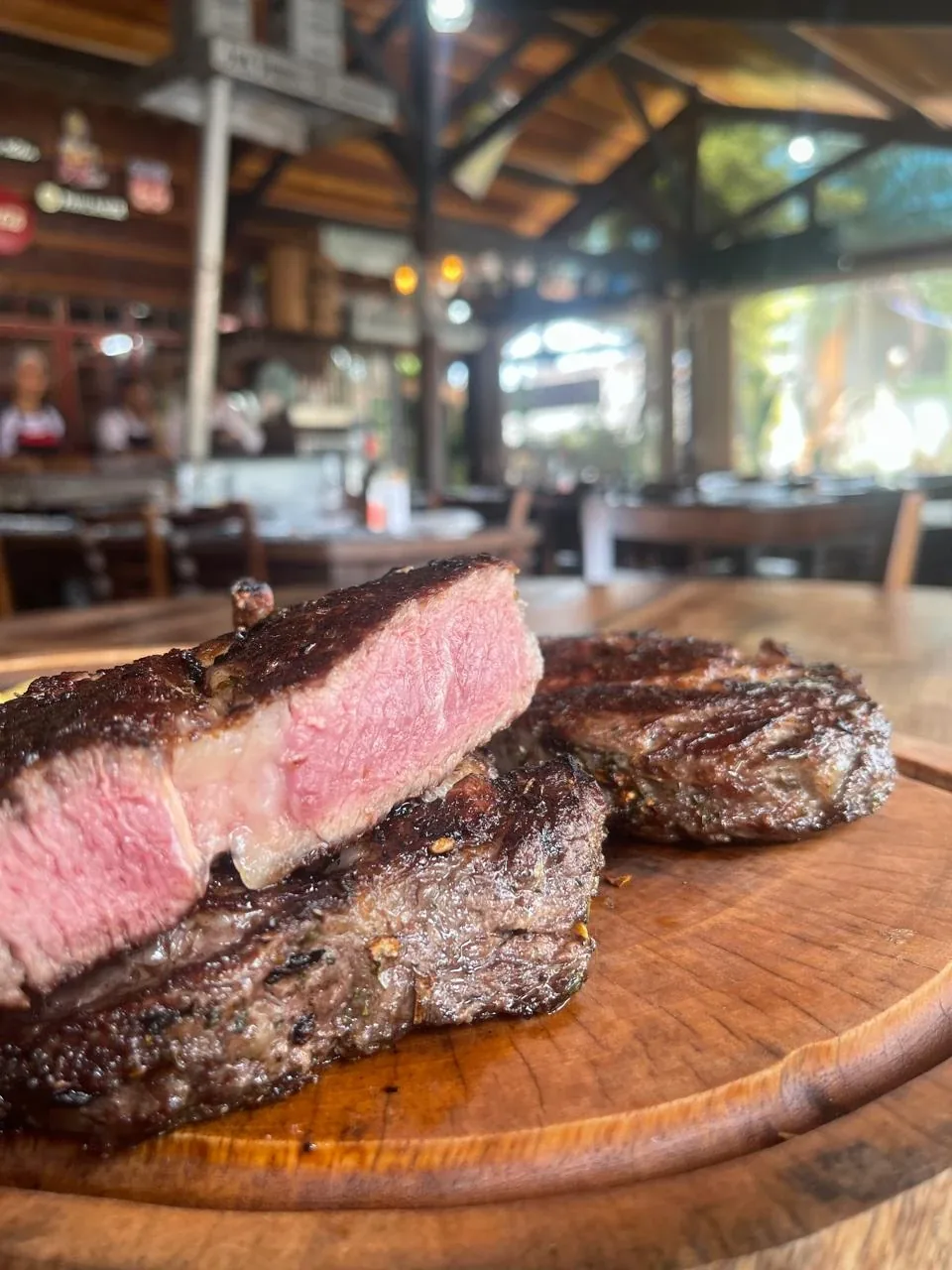 Bife Ancho ao ponto na tábua, salão do SACY GRILL ao fundo